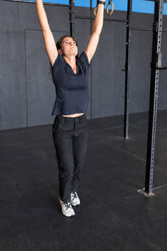 Woman wearing black MGT Gear workwear pants while doing a pull-up