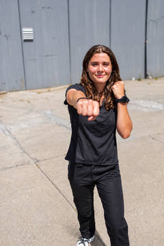 Woman wearing black MGT Gear workwear pants outdoors in an active stance